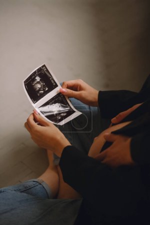 Close up photo of pregnant woman and her husband looking at the ultrasound picture. Love concept. Family concept. The concept of happy parenthood