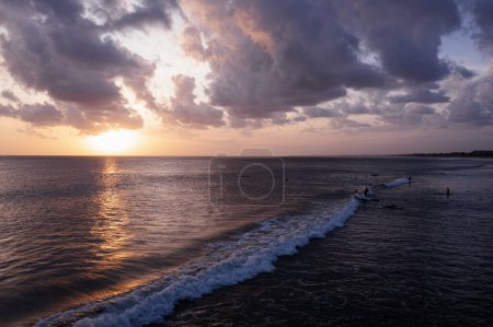 Foto de Surfistas montan las olas en el cálido mar al atardecer. - Imagen libre de derechos