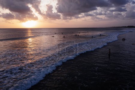 Foto de Surfistas montan las olas en el cálido mar al atardecer. - Imagen libre de derechos