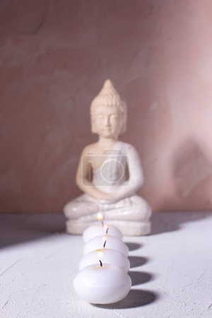 Photo for Wellness concept with  row of burning candles and statue of Buddha  on textured background.  Religion concept. Selecctive focus is on first candle. - Royalty Free Image