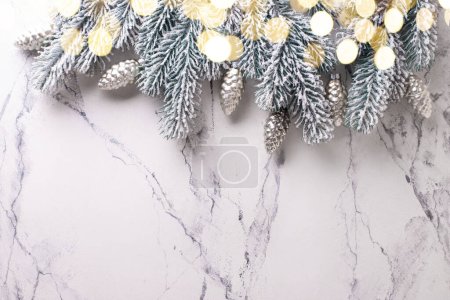 Téléchargez les photos : Bordure de branches, cônes en verre argenté et lumières bokeh sur fond d merveille blanche. Simple composition de Noël. Vue de dessus. Place pour le texte. - en image libre de droit