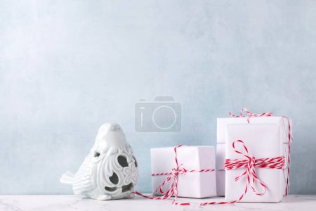 Photo for Festive postcard with  wrapped boxes with presents  and decorative blue bird against  blue textured  wall. Scandinavian style. Place for text - Royalty Free Image