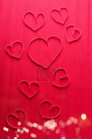 Photo for Border from pink paper hearts on red textured paper surface. Top view. Valentine day, Mothers day concept. - Royalty Free Image