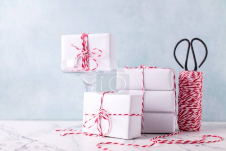 Photo for Postcard with  wrapped boxes with presents, bikers twine and scissors against  blue textured  wall. Scandinavian style. Place for text. - Royalty Free Image