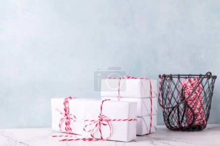 Photo for Holiday postcard with  wrapped boxes with presents, bikers twine in wire bucket against  blue textured  wall. Scandinavian style. Place for text. - Royalty Free Image