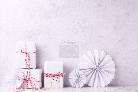 Photo for Postcard with  wrapped boxes with presents and ehandmade paper rosettas against textured  wall. Scandinavian style. Place for text - Royalty Free Image