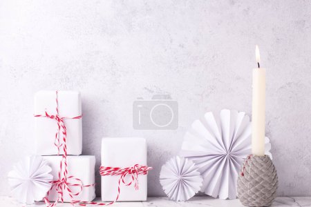 Photo for Postcard with  wrapped boxes with presents and burning candle against textured  wall. Scandinavian style. Place for text. - Royalty Free Image