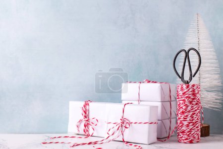 Photo for Card with  wrapped boxes with presents, bikers twine, scissors and white tree against  blue textured  wall. Scandinavian style. Place for text. - Royalty Free Image