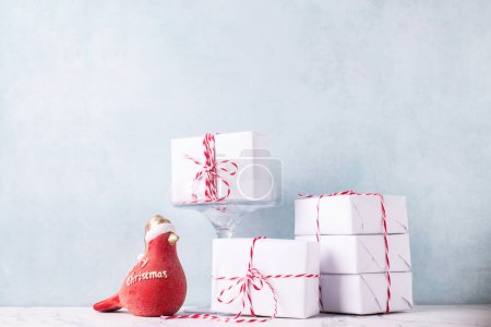 Photo for Postcard with  wrapped boxes with presents and ecorative red robin bird against  blue textured  wall. Scandinavian style. Place for text. - Royalty Free Image