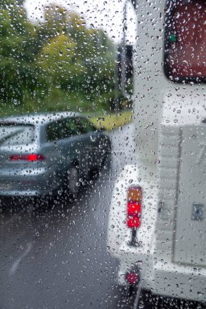 Téléchargez les photos : Vue d'une route achalandée à travers une vitre par temps pluvieux - en image libre de droit