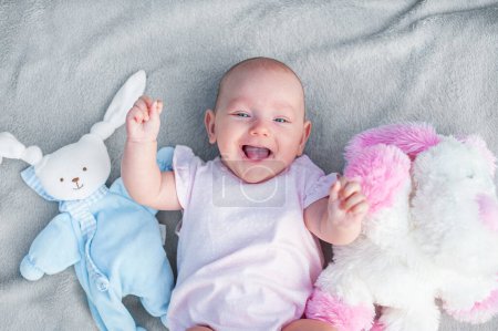 Téléchargez les photos : Bébé fille 3 mois rit avec des jouets. Soins aux nouveau-nés. - en image libre de droit