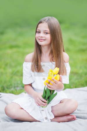Téléchargez les photos : Portrait de fille avec des tulipes jaunes dans la nature gros plan - en image libre de droit