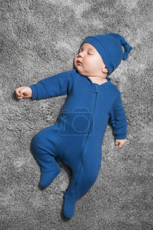 Téléchargez les photos : Newborn baby sleeps in blue overalls on gray blanket. - en image libre de droit