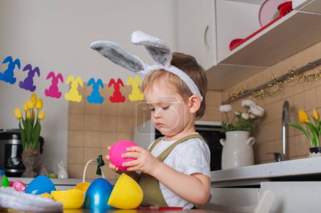 Téléchargez les photos : Petit garçon peignant Oeuf de Pâques gros plan. Traditions de Pâques et divertissement avec les enfants à la maison. - en image libre de droit