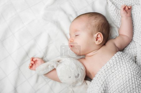Téléchargez les photos : Dormir garçon nouveau-né 2 mois avec jouet sur fond blanc fermer et copier l'espace. - en image libre de droit