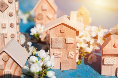 Téléchargez les photos : Blooming spring trees and miniature wooden houses close up. Springtime greeting card and copy space. - en image libre de droit