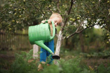 Foto de Niño pequeño riego jardín con regadera. Desarrollo de verano de niños al aire libre. - Imagen libre de derechos