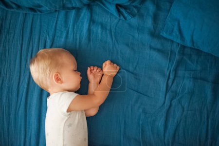 Téléchargez les photos : Bébé dort gros plan sur le lit avec plaid bleu. - en image libre de droit