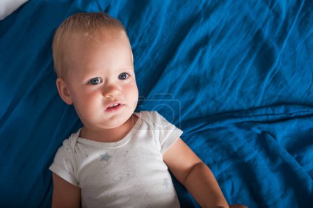 Photo for Toddler sleeps close-up on bed with blue plaid. - Royalty Free Image