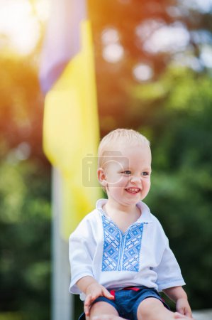Foto de Niño en vyshyvanka ucraniano en el fondo de la bandera azul-amarilla ucraniana en verano. - Imagen libre de derechos