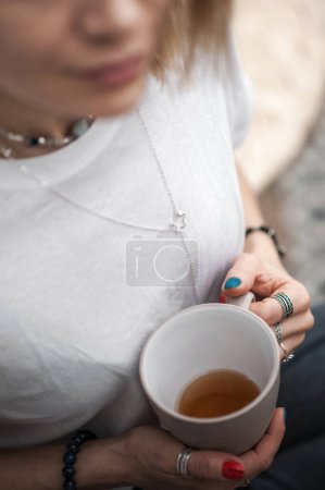 Foto de Mujer atractiva sentada pensativa y solitaria con taza de té de cerca y espacio de copia. Enfoque selectivo. - Imagen libre de derechos