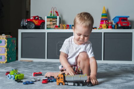 Photo for Toddler boy plays in playroom with educational toys. - Royalty Free Image
