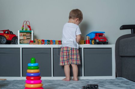 Téléchargez les photos : Tout-petit garçon joue dans la salle de jeux avec des jouets éducatifs. - en image libre de droit