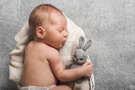 Foto de Newborn 3 weeks sleeping with rabbit toy close up. Baby care, colic, teething, healthy sleep. - Imagen libre de derechos