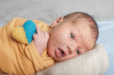 Foto de Newborn baby 14 days old with heart of color of Ukraine in his hands close-up. - Imagen libre de derechos