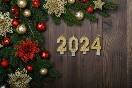Téléchargez les photos : Bonne année 2024 carte de vœux. Numéros de bougie sur fond en bois et disposition de sapin de Noël, boules, cadeaux. Fermer et copier l'espace, Mise au point sélective. - en image libre de droit