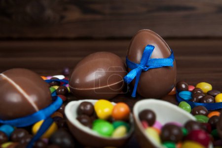 Foto de Composición de Pascua con deliciosos dulces, huevos de chocolate y lazo azul sobre fondo de madera, espacio para texto - Imagen libre de derechos