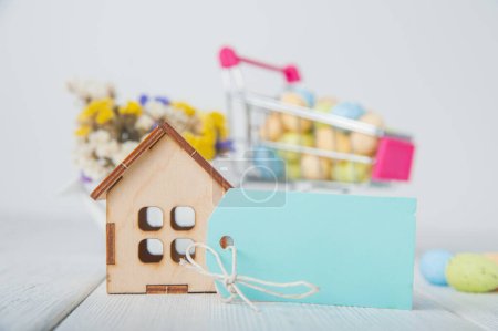 Photo for Happy Easter greeting card. Miniature wooden house. Rabbits, colorful eggs, spring flowers with tag for text. - Royalty Free Image