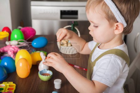 Téléchargez les photos : Toddler boy painting Easter egg close-up. Easter traditions and entertainment with children at home. - en image libre de droit