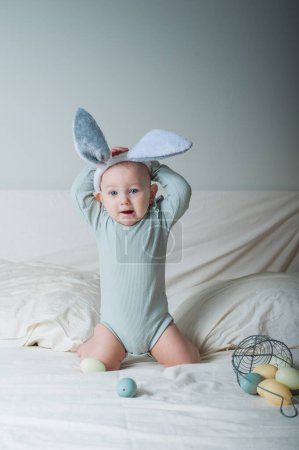 Foto de Niña de 1 año en la cama con cesta y huevos de Pascua. Caza de huevos, actividad infantil. - Imagen libre de derechos