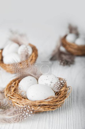 Téléchargez les photos : Happy Easter greeting card. Miniature rabbits and nests with eggs and feathers. - en image libre de droit