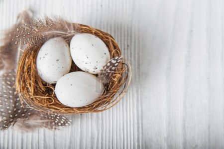 Téléchargez les photos : Happy Easter greeting card. Miniature rabbits and nests with eggs and feathers. - en image libre de droit