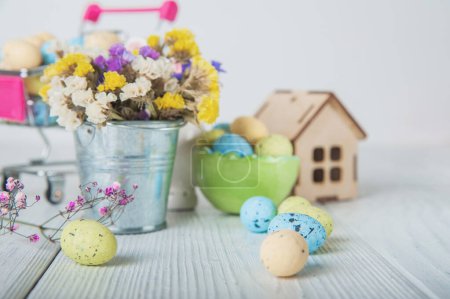 Photo for Happy Easter greeting card. Miniature wooden house. Rabbits, colorful eggs, spring flowers with tag for text. - Royalty Free Image