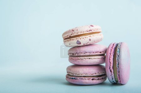 Pink macaroons on blue background close-up and empty space.