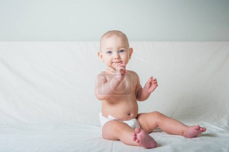 Téléchargez les photos : Bébé fille 1 an dans une couche sur le lit gros plan. - en image libre de droit
