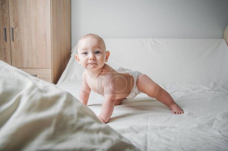 Téléchargez les photos : Bébé fille 1 an dans une couche sur le lit gros plan. - en image libre de droit