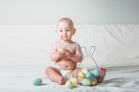 Téléchargez les photos : Bébé fille de 1 an au lit avec panier et oeufs de Pâques. Chasse aux œufs, activité pour les enfants. - en image libre de droit