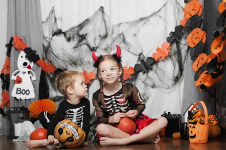 Photo for Children boy and girl with pumpkin fooling around at home on Halloween. - Royalty Free Image