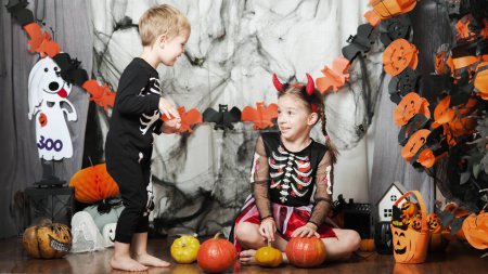 Photo for Children boy and girl with pumpkin fooling around at home on Halloween. - Royalty Free Image
