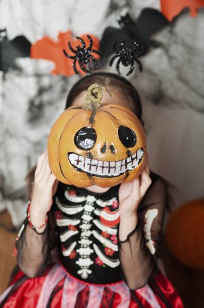 Téléchargez les photos : Fille avec citrouille tromper autour à la maison sur Halloween. - en image libre de droit