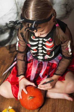 Foto de Chica pintando calabazas en casa para Halloween. - Imagen libre de derechos