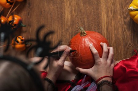 Photo for Girl painting pumpkins at home for Halloween. - Royalty Free Image