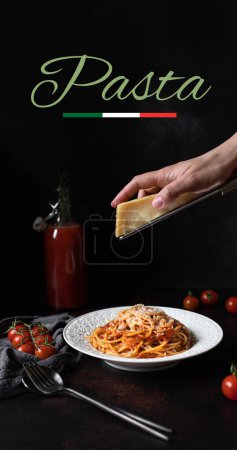 Foto de Pasta con salsa de tomate y parmesano. Plato blanco con espaguetis sobre fondo oscuro con la palabra pasta. Manos rallando queso parmesano en una pasta de espaguetis. Comida tradicional italiana - Imagen libre de derechos