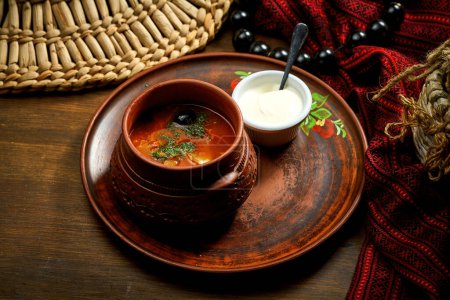 Téléchargez les photos : Solyanka meat soup with olives, lemon, smoked sausages in a bowl. Wooden background - en image libre de droit