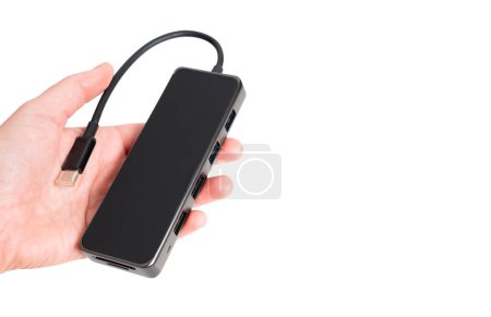 Hand holding a black aluminum multiport usb-c hub adapter isolated on white background with copy space.