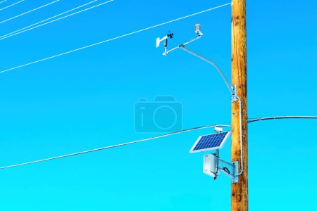 Photo for Solar panel and auxiliary equipment installed on a wooden pole of an electric power line against a vibrant blue sky. - Royalty Free Image